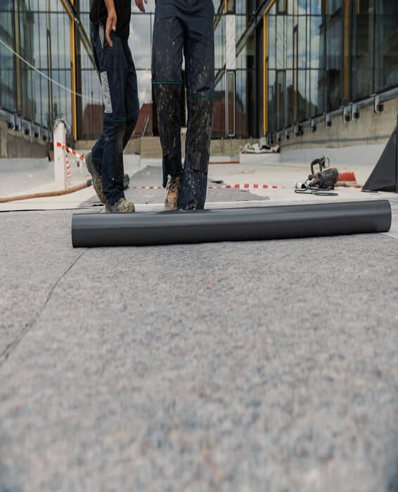 two roofers spreading out an EPDM roll